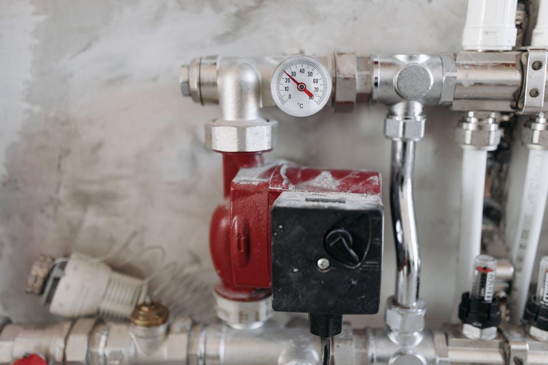 Free Close-up view of an industrial plumbing system featuring a pressure gauge and steel pipes. Stock Photo